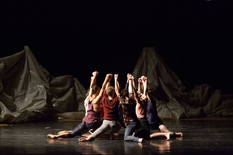 The group of dancers lungefacing into a circle and hold hands above their heads